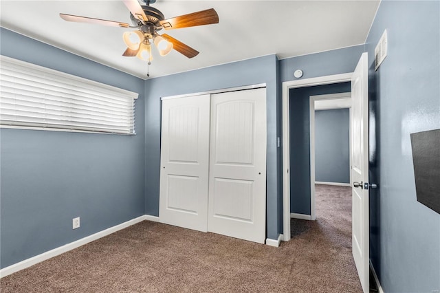 unfurnished bedroom featuring dark colored carpet, a closet, a ceiling fan, and baseboards