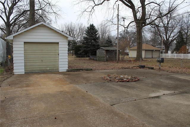 detached garage featuring driveway and fence