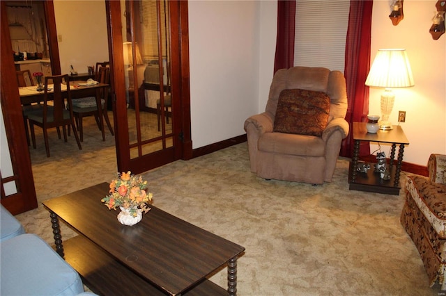 living area featuring light carpet and baseboards