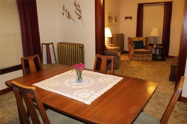 dining space featuring baseboards, radiator heating unit, and light colored carpet