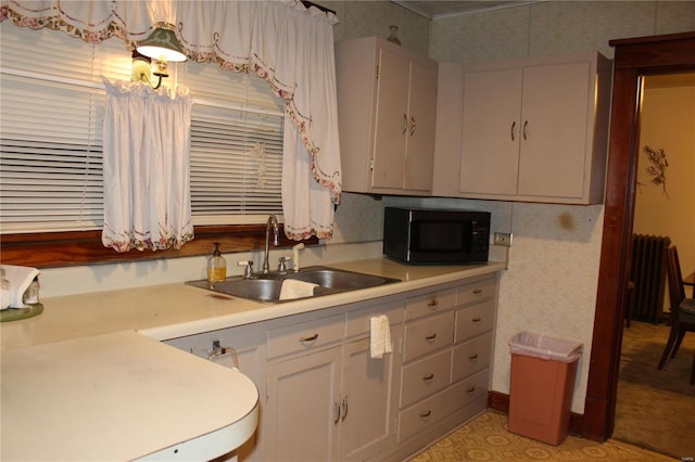 kitchen with black microwave, light countertops, a sink, and radiator