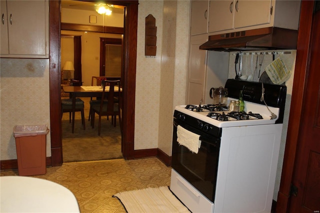 kitchen featuring wallpapered walls, baseboards, ventilation hood, light countertops, and gas stove