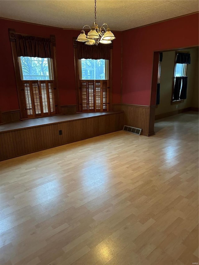 interior space featuring an inviting chandelier, light hardwood / wood-style floors, a textured ceiling, and a wealth of natural light