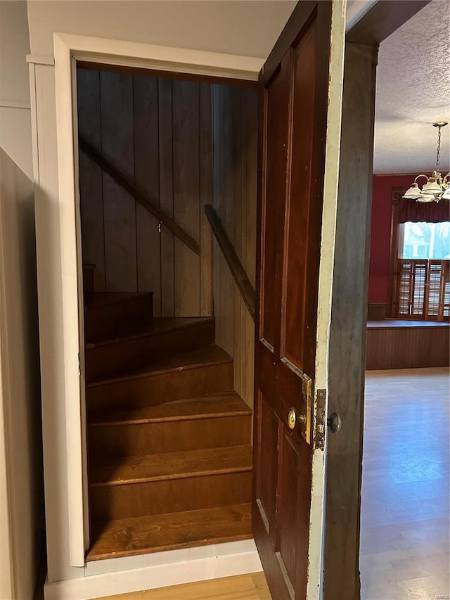 stairs featuring a textured ceiling and a chandelier