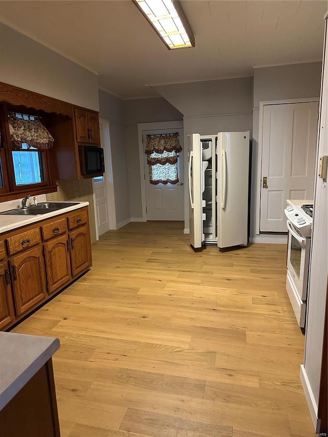 kitchen with sink, white appliances, and light hardwood / wood-style floors