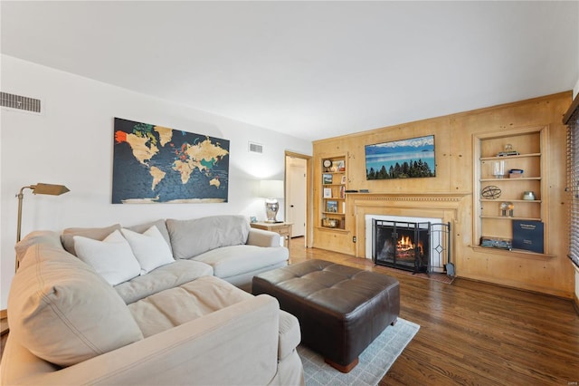 living room with dark hardwood / wood-style flooring and built in shelves