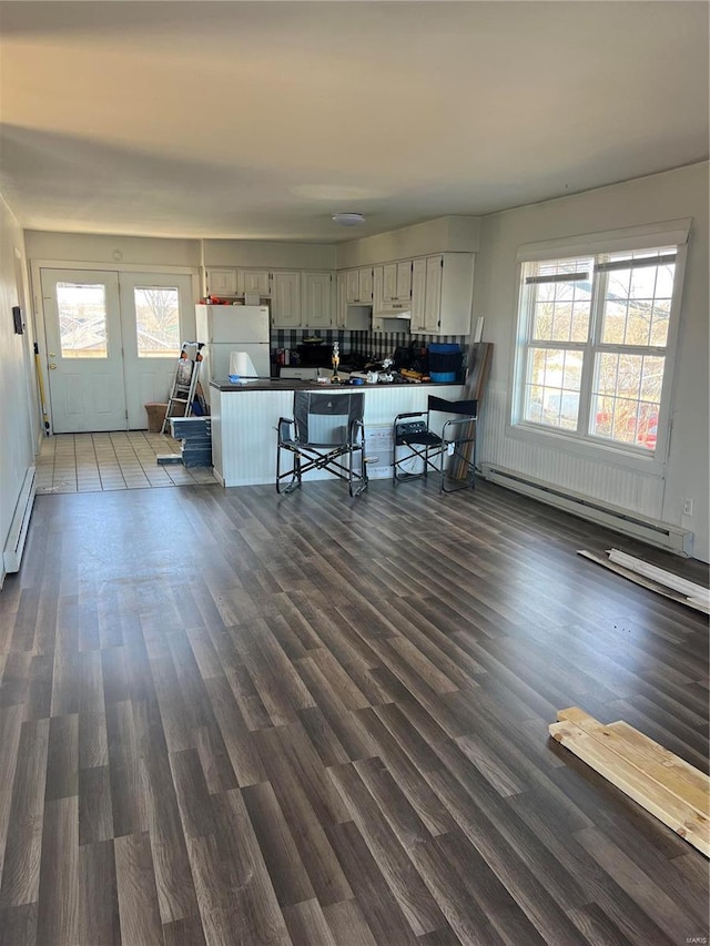 kitchen featuring plenty of natural light, dark countertops, a baseboard radiator, a breakfast bar, and freestanding refrigerator