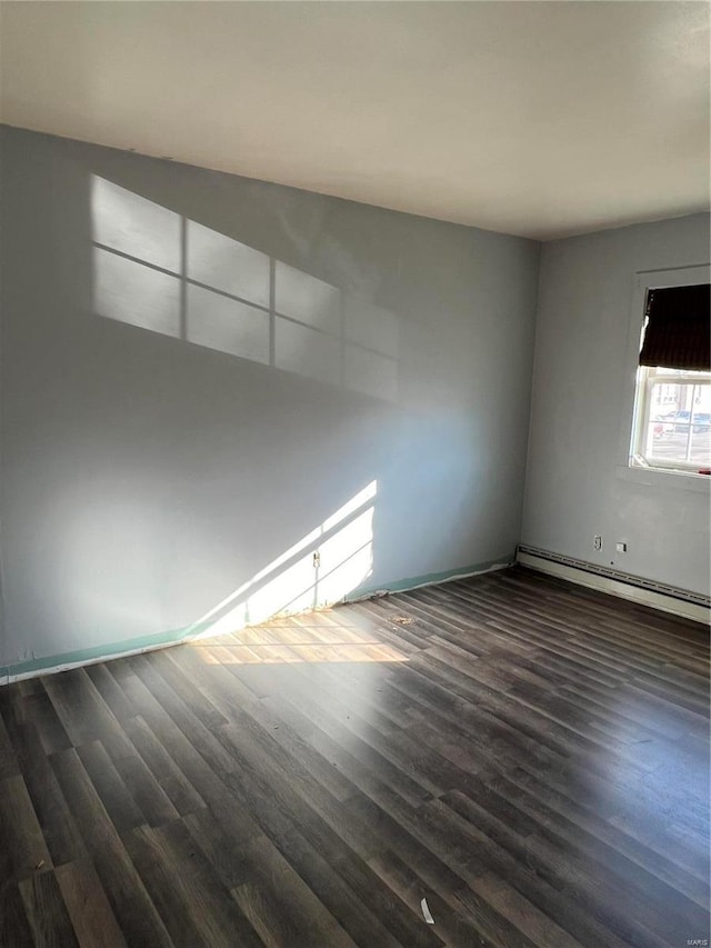 spare room featuring a baseboard radiator and dark wood-style flooring