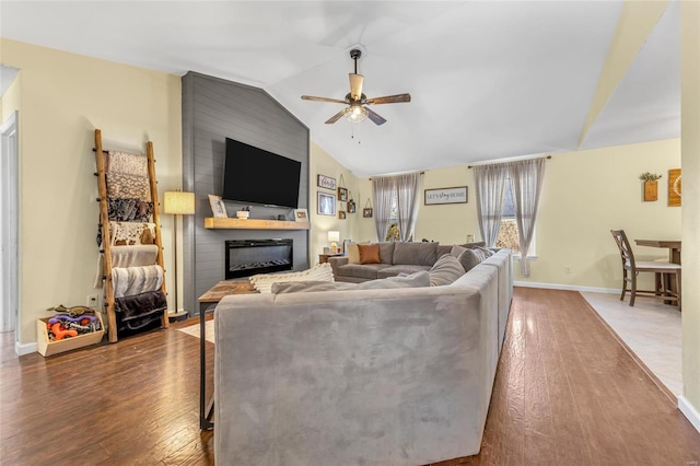 living room with lofted ceiling, dark wood-type flooring, a fireplace, and ceiling fan