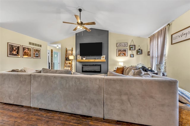 living room featuring dark wood-type flooring, ceiling fan, a large fireplace, and vaulted ceiling