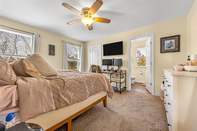 carpeted bedroom with multiple windows, ensuite bathroom, and ceiling fan