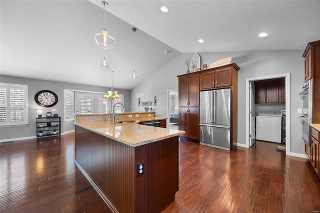 kitchen featuring a large island with sink, high quality fridge, hanging light fixtures, and a sink