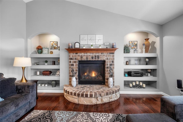 living room featuring lofted ceiling, built in shelves, hardwood / wood-style flooring, and baseboards