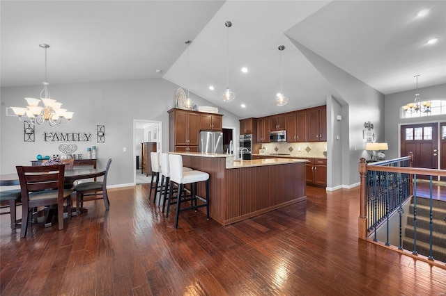 kitchen featuring a breakfast bar area, pendant lighting, stainless steel appliances, and a notable chandelier