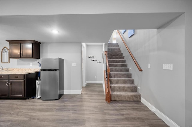 kitchen featuring light wood-style floors, baseboards, dark brown cabinets, and freestanding refrigerator