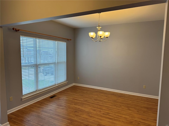 unfurnished room with an inviting chandelier and hardwood / wood-style flooring