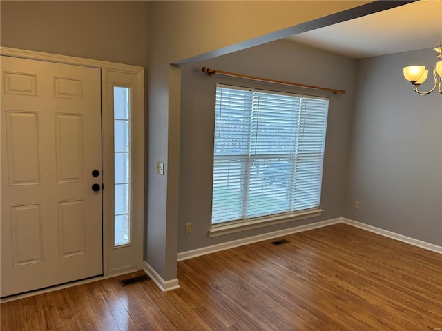 foyer with wood-type flooring, plenty of natural light, and a notable chandelier