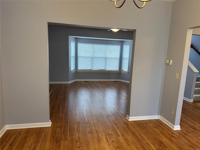 spare room featuring wood finished floors, baseboards, and stairs