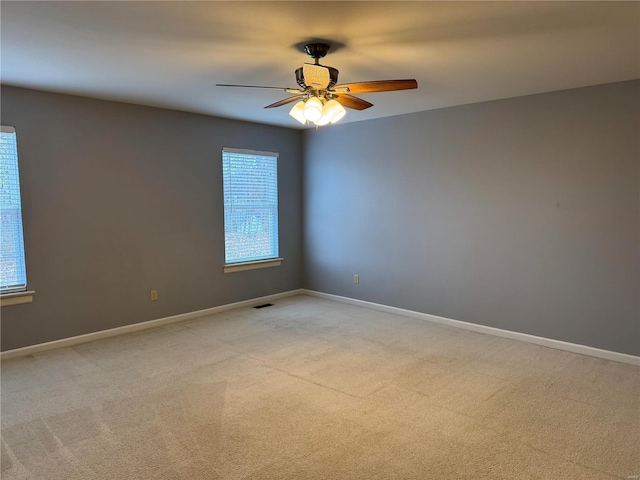 unfurnished room with ceiling fan, visible vents, baseboards, and light colored carpet