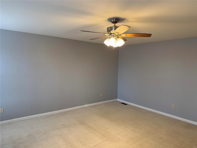 spare room featuring light carpet, a ceiling fan, visible vents, and baseboards