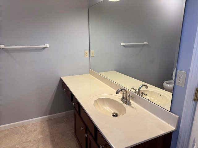 bathroom featuring toilet, baseboards, and vanity