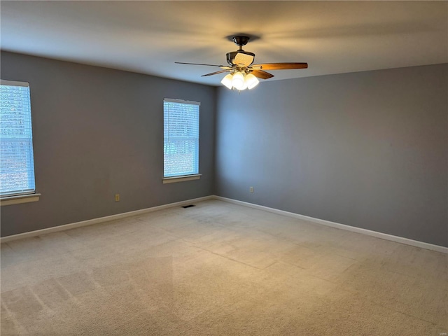 empty room with a ceiling fan, light carpet, and baseboards