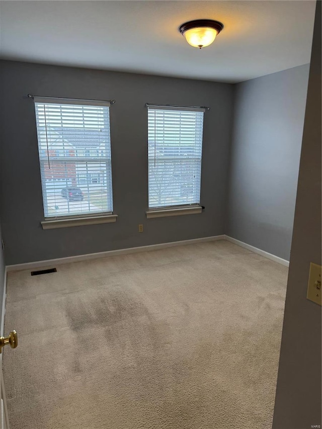 carpeted empty room with visible vents and baseboards