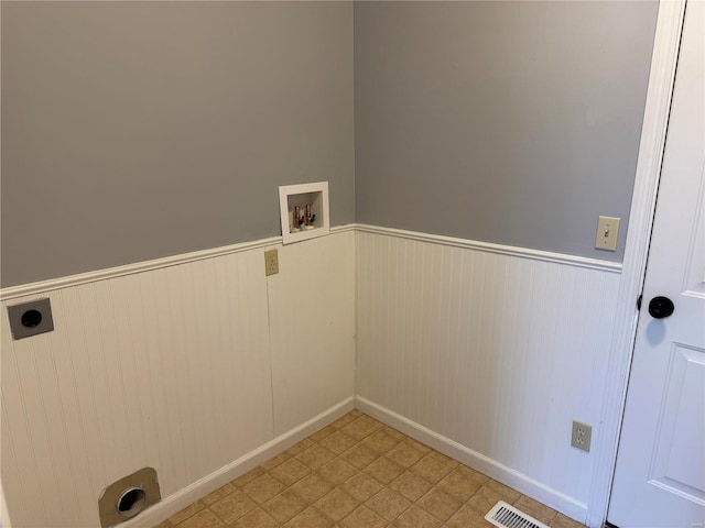 clothes washing area with a wainscoted wall, laundry area, washer hookup, visible vents, and electric dryer hookup