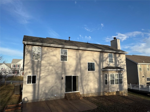 rear view of property with entry steps and a chimney