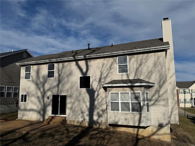 rear view of house featuring entry steps and a chimney