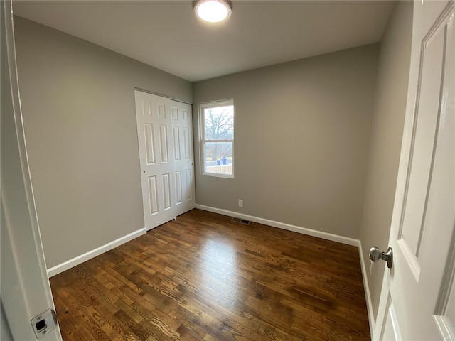 unfurnished bedroom with dark wood-type flooring and a closet