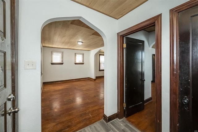 hall with wooden ceiling, baseboards, arched walkways, and dark wood-type flooring