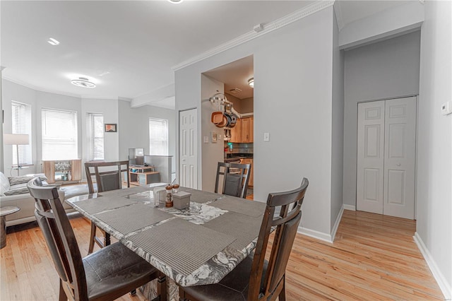 dining room featuring baseboards, crown molding, and light wood finished floors