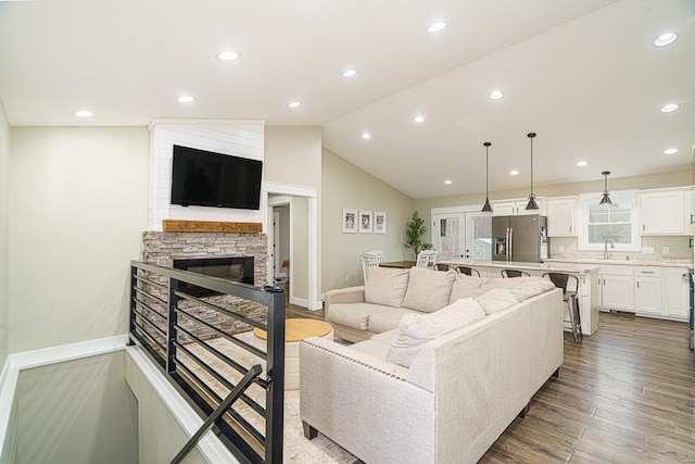 living room with lofted ceiling, sink, a fireplace, and hardwood / wood-style floors