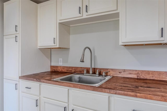 kitchen featuring white cabinetry, sink, and wooden counters