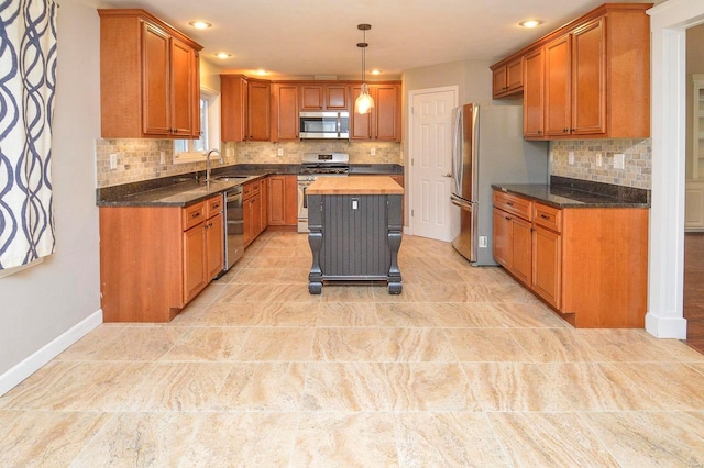 kitchen with dark stone countertops, hanging light fixtures, sink, and appliances with stainless steel finishes