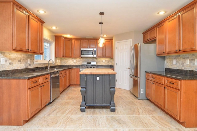 kitchen with a kitchen island, appliances with stainless steel finishes, wood counters, decorative light fixtures, and sink