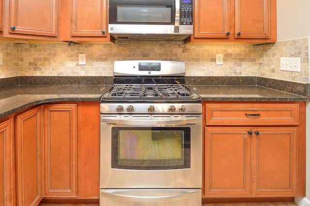 kitchen with stainless steel appliances, tasteful backsplash, and dark stone countertops