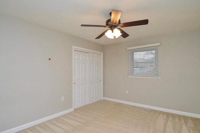 unfurnished bedroom featuring ceiling fan, a closet, and light carpet