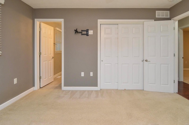 unfurnished bedroom with light colored carpet and a closet