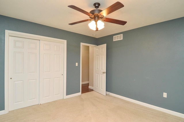 unfurnished bedroom featuring light carpet, ceiling fan, and a closet