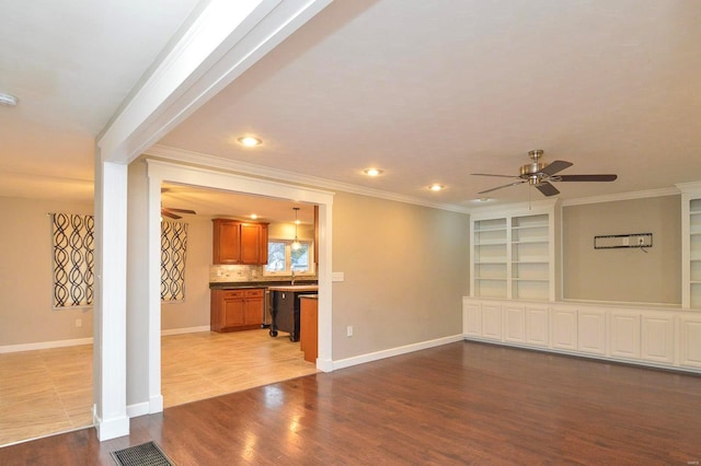 unfurnished living room featuring crown molding, built in shelves, ceiling fan, and light wood-type flooring