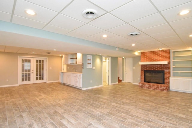 unfurnished living room featuring french doors, a fireplace, and light hardwood / wood-style flooring