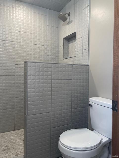 bathroom featuring toilet and a tile shower