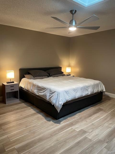 bedroom featuring ceiling fan, a textured ceiling, and light wood-type flooring