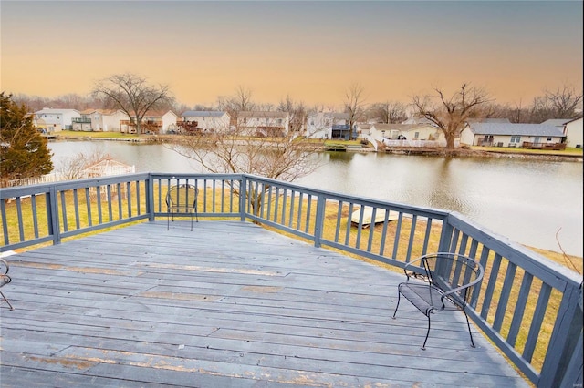 deck at dusk featuring a water view