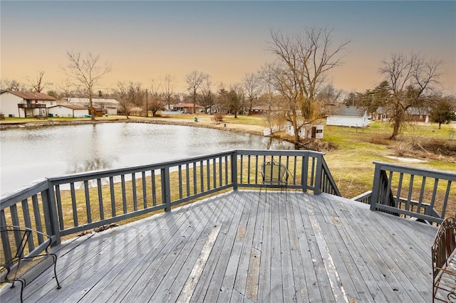 deck at dusk with a lawn and a water view