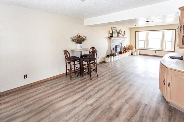 dining area featuring a fireplace, sink, light hardwood / wood-style flooring, and a textured ceiling