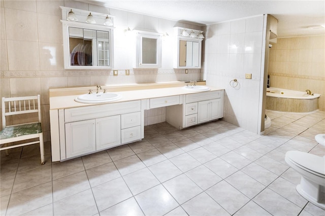 bathroom with tile patterned floors, tile walls, a textured ceiling, vanity, and tiled bath