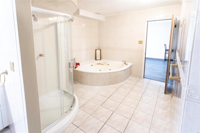 bathroom with tile walls, tile patterned flooring, and shower with separate bathtub